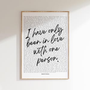 May include: A framed print with a light wood-colored frame. The print features a background of small text with the handwritten phrase, "I have only been in love with one person." The text "Heated Rivalry" is at the bottom.