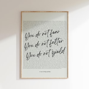 May include: Framed art print with a light beige border. The artwork features a background of printed text with the phrases "You do not fear", "You do not falter", and "You do not yield" in elegant script. The title "A Court of Wings and Ruin" is at the bottom.