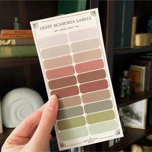 May include: A sticker sheet with 18 rectangular labels in various shades of brown, beige, and green. The sheet is titled "Light Academia Labels - sticker sheet" and has the text "The Naturalist's Guild" at the bottom.