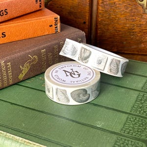 May include: Washi tape with seashell designs, labelled "An Emporium of the Natural World." The tape is shown on a green book, with other books in the background. The image also shows the text "EUROPE" and "BRITAIN".