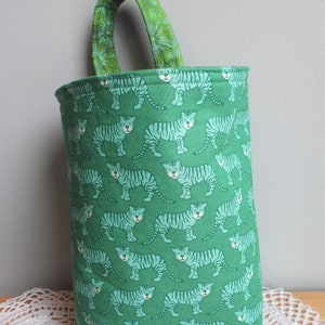 May include: A green fabric tote bag with a white tiger print. The bag has a green fabric handle.