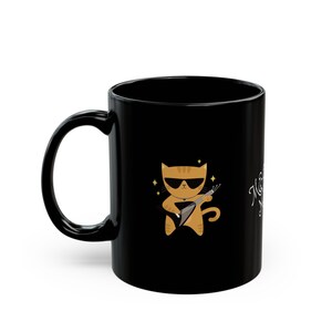 May include: Black coffee mug with a cartoon orange cat wearing sunglasses and playing a guitar. The text "Music is my therapy" is on the mug.
