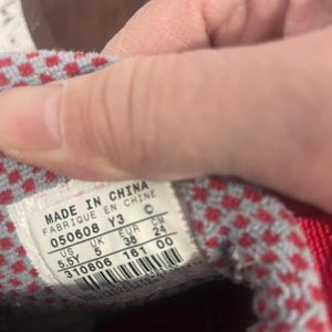 K&ouml;nnte beinhalten: Nahaufnahme eines Schuhlabels mit der Aufschrift "MADE IN CHINA" und Gr&ouml;&szlig;enangaben. Das Etikett zeigt die EUR-Gr&ouml;&szlig;e 38 (entspricht ca. 24 cm), US 5.5Y und UK 5. Das Innere des Schuhs hat rot-grau karierten Stoff.