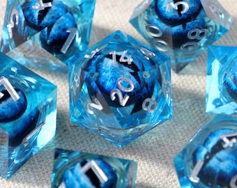 May include: A set of seven translucent blue polyhedral dice, each containing a realistic blue eye with a black pupil suspended inside. The dice feature sharp edges and clear, silver-colored numbers etched into the surfaces for readability.