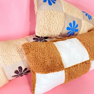 May include: Three patchwork pillows with different colored fabrics and smiling flower designs. The pillows are made of a soft, fluffy material and are perfect for adding a touch of whimsy to any room.