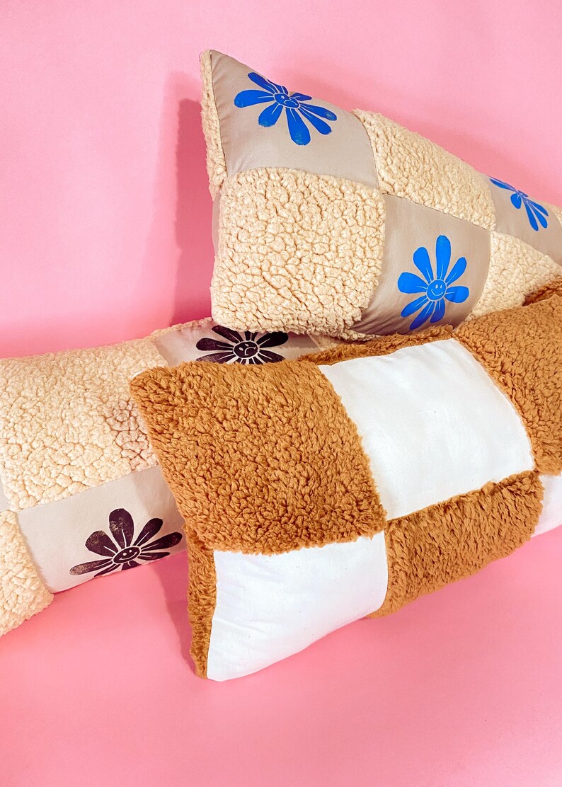 May include: Three patchwork pillows with different colored fabrics and smiling flower designs. The pillows are made of a soft, fluffy material and are perfect for adding a touch of whimsy to any room.