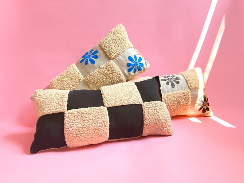 May include: Two decorative pillows with a patchwork design. One pillow is beige and black checkered, the other is beige with blue and white flowers.