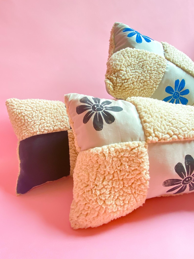 May include: Three decorative pillows with a patchwork design. The pillows are made of a soft, fluffy material and feature black and blue flower designs.