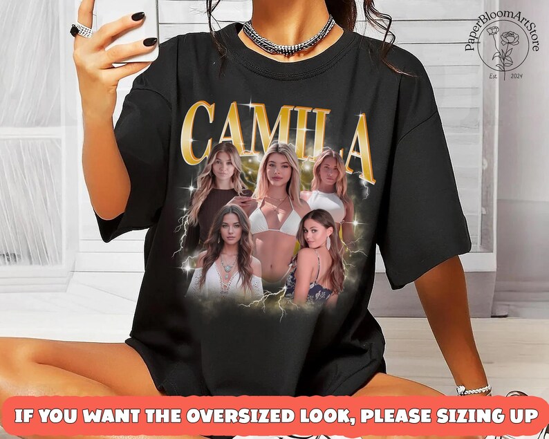 May include: Black oversized t-shirt featuring the name "CAMILA" in gold lettering with a vintage design. The shirt includes images of several women and the text "IF YOU WANT THE OVERSIZED LOOK, PLEASE SIZING UP".
