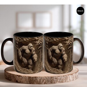 May include: Two black-handled coffee mugs with a detailed image of a gorilla in a forest setting. The gorilla is brown and appears to be carved into the mug's surface. The mugs are displayed on a wooden coaster.