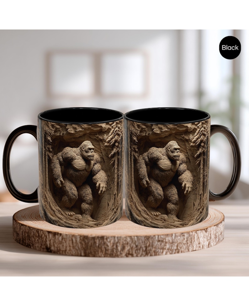 May include: Two black-handled coffee mugs with a detailed image of a gorilla in a forest setting. The gorilla is brown and appears to be carved into the mug's surface. The mugs are displayed on a wooden coaster.