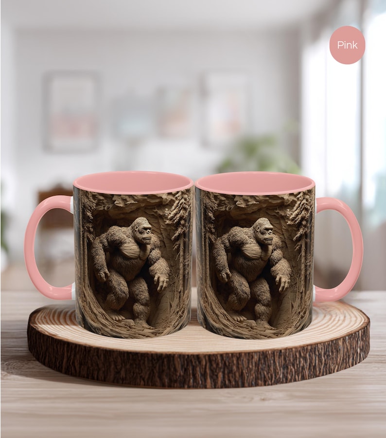 May include: Two pink-handled coffee mugs with a detailed image of a gorilla in a forest setting. The mugs are displayed on a wooden coaster with a natural edge. The interior of the mugs is also pink.
