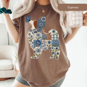 Puede incluir: Una camiseta de manga corta color espresso con un gráfico de la silueta de un perro relleno de un patrón de patchwork floral azul y blanco. Una mariposa azul descansa sobre la nariz del perro y el nombre Cooper está escrito en cursiva.