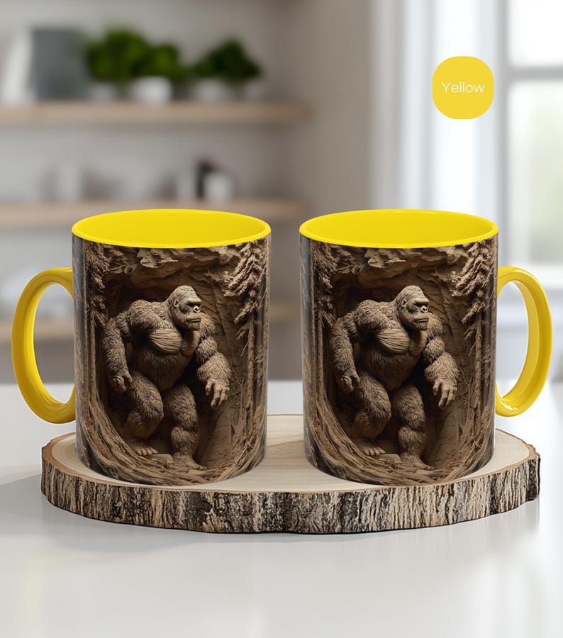 May include: Two ceramic mugs with a yellow interior and handle. The exterior features a detailed illustration of a gorilla in a forest setting. The mugs are displayed on a wooden coaster, with a yellow circle that says "Yellow".