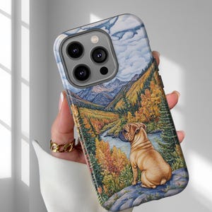 May include: A phone case featuring a scenic landscape with a pug dog. The case displays a mountain range, river, and autumn trees in shades of green, yellow, and orange. The pug is light brown and sits on a rock.