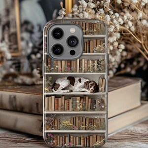 May include: A phone case with a bookshelf design and a sleeping dog. The case shows a white bookshelf filled with old books and flowers. The dog is brown and white, resting on a shelf.