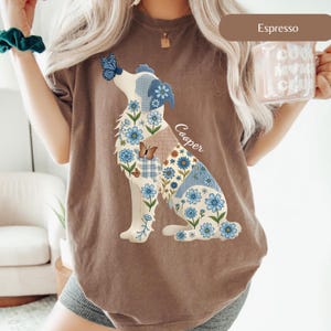 May include: An espresso brown t-shirt featuring a graphic of a dog sitting in profile. The dog is filled with a pattern of blue flowers, blue and white gingham, and brown plaid. A blue butterfly rests on the dog's nose, and the name Cooper is printed.