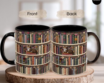 May include: A black coffee mug with a wraparound design of a bookshelf filled with books, flowers, and a cat. The mug has a black handle and interior. The mug is displayed on a wooden slice, showcasing the front and back designs.