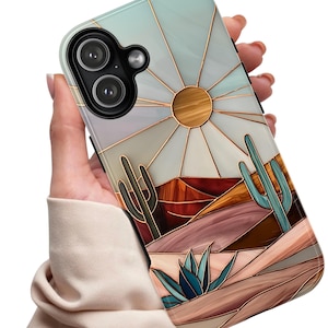 May include: A phone case featuring a stained-glass style desert landscape with a golden sun, two tall green cacti, and a small agave plant in the foreground. The design uses segmented panels in shades of beige, brown, and teal, separated by thin metallic lines.