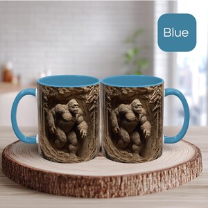May include: Two blue-handled coffee mugs with a detailed image of a gorilla in a cave setting. The mugs have a blue interior and are displayed on a wooden coaster. The word "Blue" is in a blue square in the background.