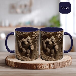 May include: Two navy blue coffee mugs with a detailed illustration of a gorilla in a forest setting. The mugs are displayed on a wooden coaster. The word "Navy" is in a navy blue square in the background.