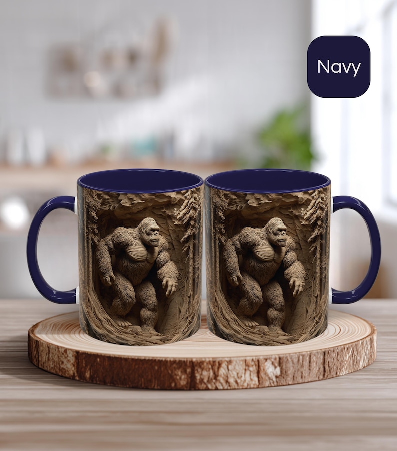 May include: Two navy blue coffee mugs with a detailed illustration of a gorilla in a forest setting. The mugs are displayed on a wooden coaster. The word "Navy" is in a navy blue square in the background.