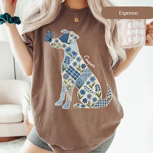 May include: An espresso-coloured short-sleeve t-shirt featuring a graphic of a dog composed of blue floral and plaid patchwork patterns. A blue butterfly rests on the dog's nose, and the name Cooper is written in white script next to the dog.