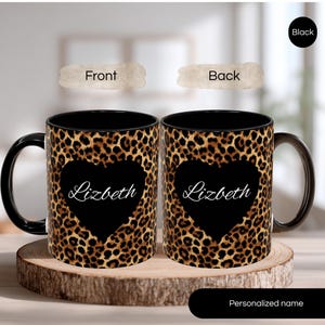 May include: A black coffee mug with a leopard print design and a black heart shape with the name "Lizbeth" in white script. The mug is displayed on a wooden slice.