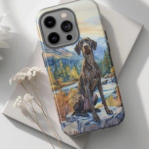 May include: A phone case featuring a detailed painting of a brown dog sitting on a rock with a scenic mountain and river background. The case has a glossy finish and a camera cutout.