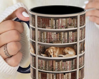 May include: A white ceramic mug with a black interior and a wraparound design of a bookshelf filled with books and flowers. A golden retriever dog is sleeping on one of the shelves. The mug is being held by a person.