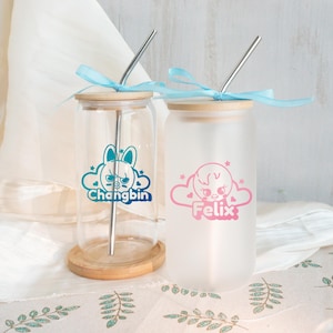 May include: Two glass drinking cups with bamboo lids and metal straws. One cup is clear with a teal graphic and the name "Changbin". The other is frosted with a pink graphic and the name "Felix". Both have blue ribbons.