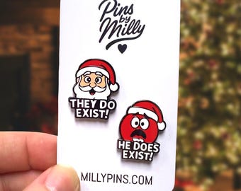 Può includere: Una scheda bianca con due spille smaltate a tema natalizio. Una spilla raffigura Babbo Natale con la scritta "THEY DO EXIST!" e l'altra un volto rosso e sorpreso con la scritta "HE DOES EXIST!". La scheda presenta anche la scritta "Pins by Milly" e "MILLY PINS.COM".