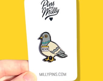 Puede incluir: Un pin de esmalte de paloma con el nombre "Kevin" en una etiqueta. El pin está sobre una tarjeta blanca con el texto "Pins by Milly". El fondo es amarillo.