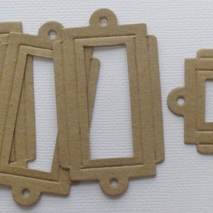 May include: Six brown paper label tags with a rectangular opening in the center. The tags have a decorative edge and a hole at the top for hanging.