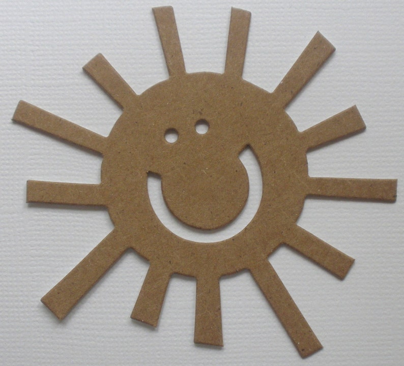 May include: A brown paper cutout of a sun with a smiling face. The sun has 16 rays.