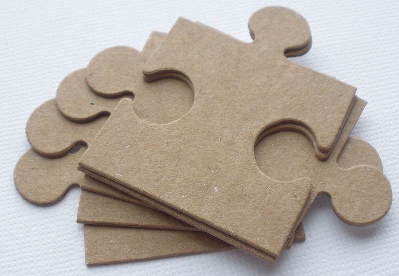 K&ouml;nnte beinhalten: Ein Stapel aus sechs braunen Papppuzzleteilen. Die Teile sind puzzleartig geformt, mit einem gro&szlig;en Teil oben und f&uuml;nf kleineren Teilen darunter.