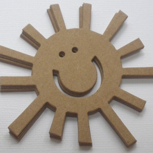 May include: A brown paper sun with a smiling face cut out of the center. The sun has 12 rays.