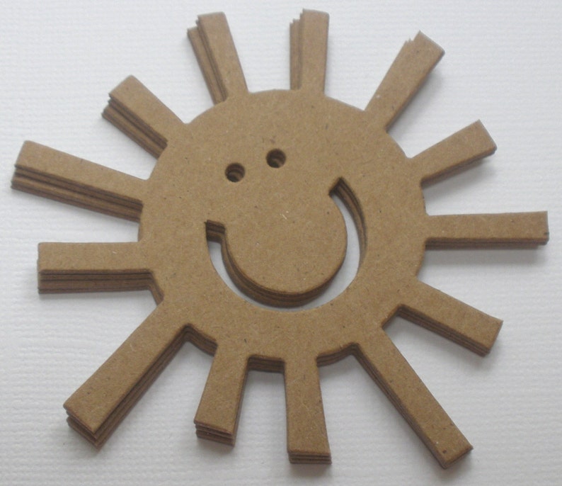 May include: A brown paper sun with a smiling face cut out of the center. The sun has 12 rays.