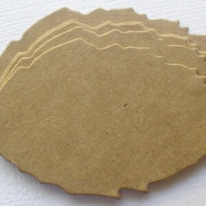 May include: A stack of six unfinished wood leaves, each with a unique, slightly irregular shape. The leaves are a light brown color and have a rough, textured surface.