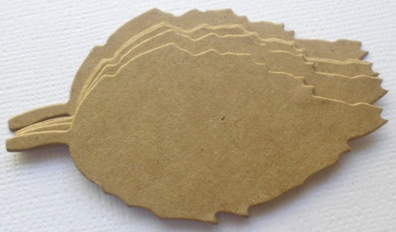 May include: A stack of six unfinished wood leaves, each with a unique, slightly irregular shape. The leaves are a light brown color and have a rough, textured surface.