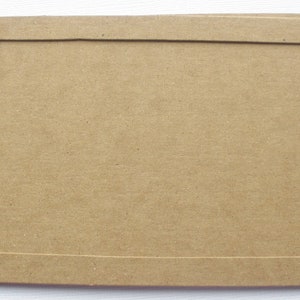 May include: A stack of brown cardboard picture frames with a simple rectangular opening.