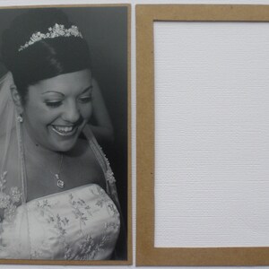 May include: A black and white photo of a bride wearing a white wedding dress with a veil and a tiara. She is smiling and looking down.