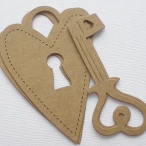 May include: A brown paper heart with a keyhole cutout and a brown paper key with a heart-shaped loop. The heart has a stitched edge.