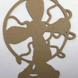 May include: A brown cardboard cutout of a vintage fan with a circular blade and a base.