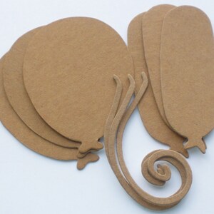 May include: A set of six brown paper balloon cutouts with curled tails. The balloons are layered on top of each other.