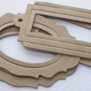 May include: A set of three brown paper craft tags with scalloped edges. One tag is oval shaped and the other two are rectangular with a decorative border.