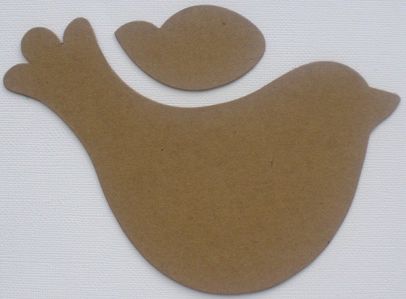 May include: A brown paper cutout of a bird with a smaller bird cutout on top. The bird is facing right and has a rounded body and a long, thin beak.