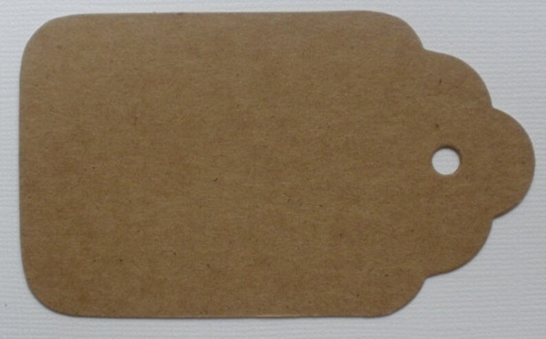May include: A brown paper gift tag with a hole punched in the top right corner. The tag has a scalloped edge.