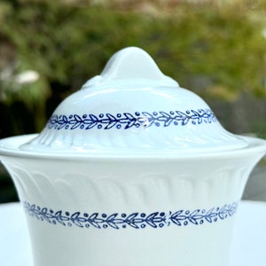 Peut inclure: Sucrier en céramique blanche avec un motif floral bleu et blanc. Le bol a un couvercle avec un bouton sur le dessus.