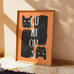 May include: A black and orange print with two black cats hanging upside down. The text "Curious" is written in white letters on an orange background.